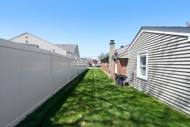 view of yard with central AC and fence