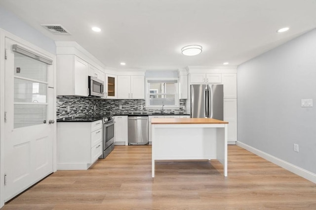 kitchen featuring visible vents, decorative backsplash, white cabinets, a sink, and appliances with stainless steel finishes