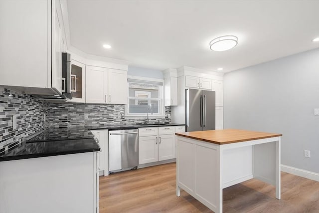 kitchen with white cabinetry, appliances with stainless steel finishes, a sink, and tasteful backsplash