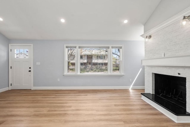 unfurnished living room featuring a brick fireplace, recessed lighting, and light wood-style floors