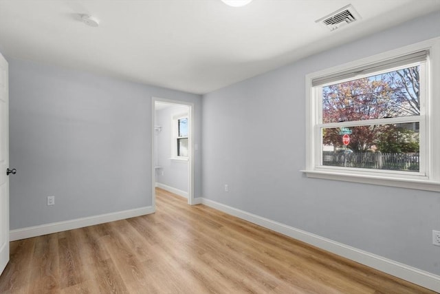 unfurnished room featuring baseboards, light wood finished floors, and visible vents