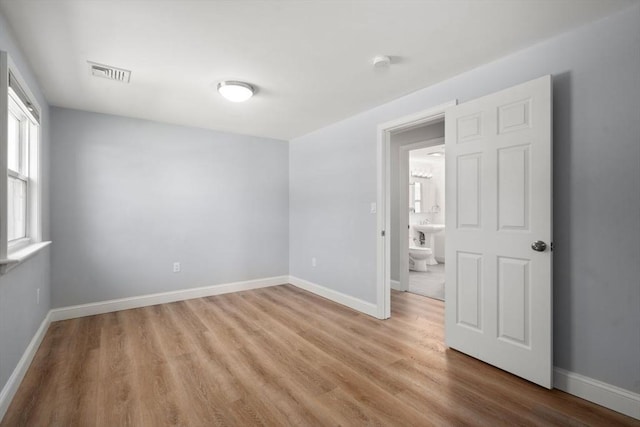 empty room featuring baseboards, visible vents, and light wood-type flooring