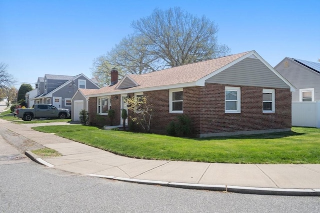 single story home featuring brick siding, a chimney, a shingled roof, and a front yard