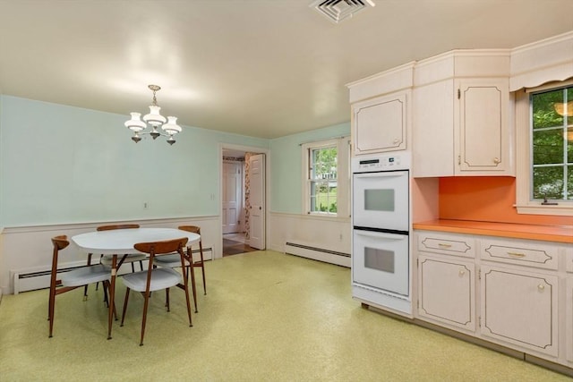 kitchen featuring white double oven, an inviting chandelier, white cabinets, hanging light fixtures, and a baseboard radiator