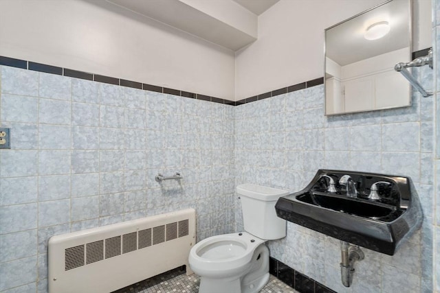 bathroom with radiator, sink, tile walls, tile patterned flooring, and toilet