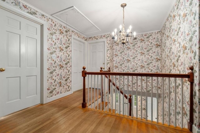 hall with hardwood / wood-style floors, a notable chandelier, and crown molding