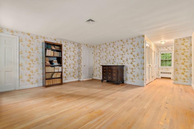 unfurnished living room with wood-type flooring and radiator heating unit