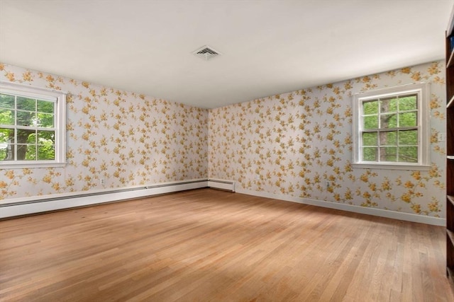 spare room featuring a healthy amount of sunlight, a baseboard radiator, and light wood-type flooring