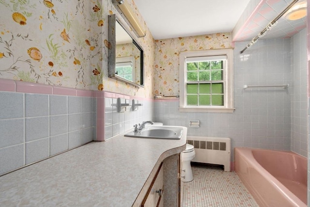 bathroom with radiator heating unit, tile patterned flooring, toilet, vanity, and tile walls