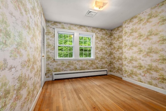 unfurnished room with light hardwood / wood-style floors and a baseboard heating unit