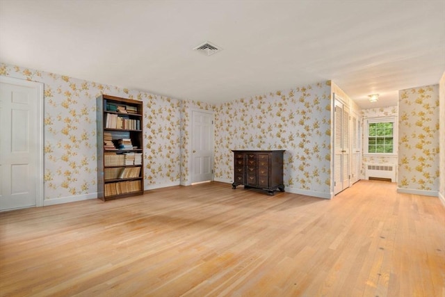 unfurnished living room featuring wood-type flooring and radiator heating unit