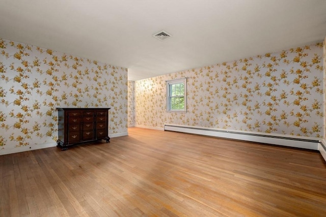 empty room with hardwood / wood-style flooring and a baseboard heating unit