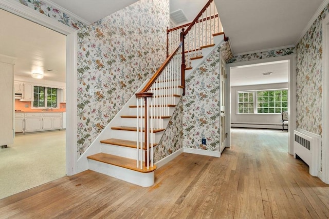 stairs with hardwood / wood-style floors, plenty of natural light, radiator, and a baseboard radiator