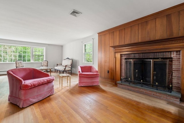 living room featuring light hardwood / wood-style floors, a brick fireplace, plenty of natural light, and a baseboard radiator