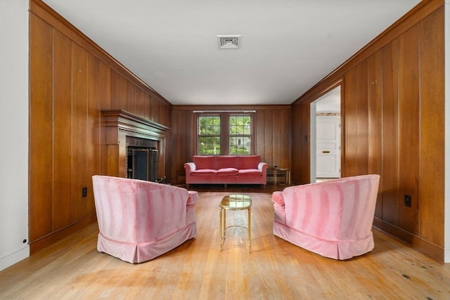 living room featuring wooden walls, crown molding, and light wood-type flooring