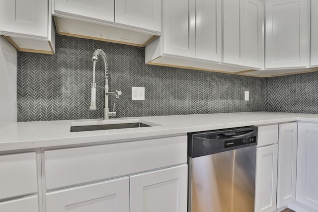 kitchen with stainless steel dishwasher, decorative backsplash, white cabinets, and sink