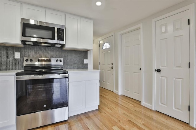 kitchen with backsplash, light hardwood / wood-style flooring, white cabinets, and stainless steel appliances