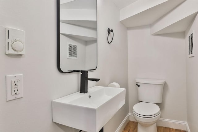 bathroom featuring toilet, wood-type flooring, and sink