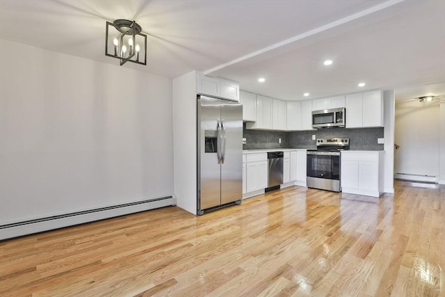 kitchen with white cabinetry, stainless steel appliances, a notable chandelier, and light wood-type flooring