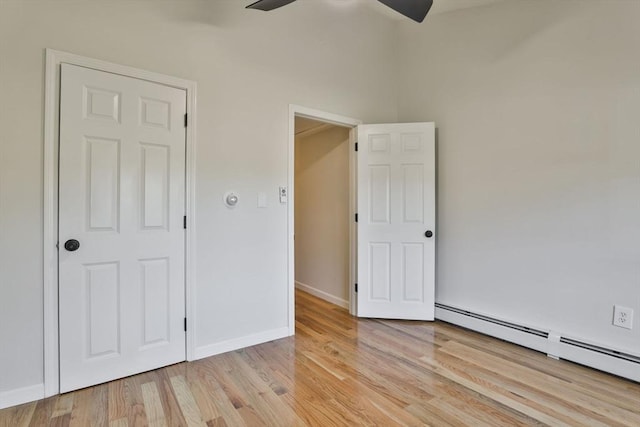 unfurnished bedroom featuring light hardwood / wood-style floors, ceiling fan, and a baseboard heating unit