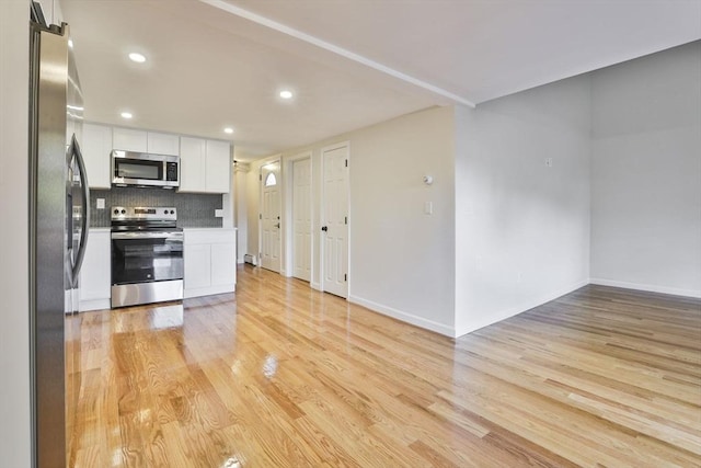 kitchen featuring decorative backsplash, white cabinetry, stainless steel appliances, and light hardwood / wood-style floors