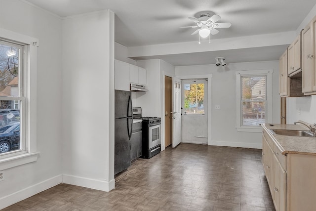 kitchen featuring black refrigerator, sink, ceiling fan, and stainless steel gas range oven