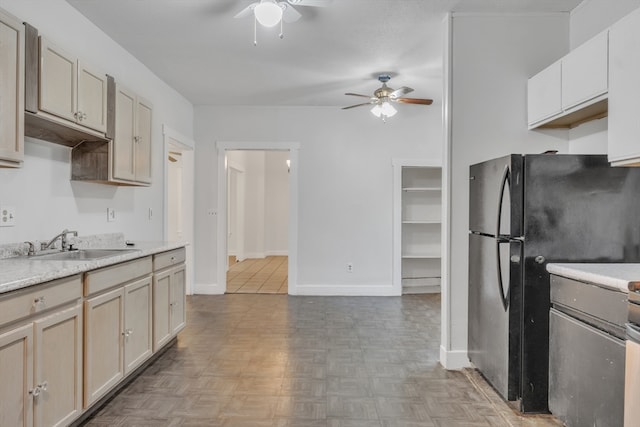 kitchen featuring ceiling fan, black fridge, sink, and light parquet flooring