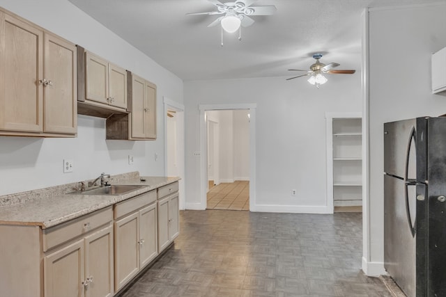 kitchen with black fridge, sink, ceiling fan, light parquet flooring, and light brown cabinetry