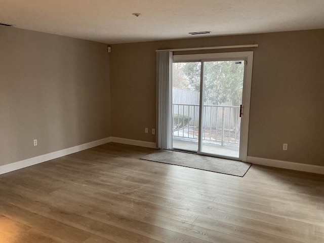 unfurnished room with light wood-type flooring, visible vents, and baseboards