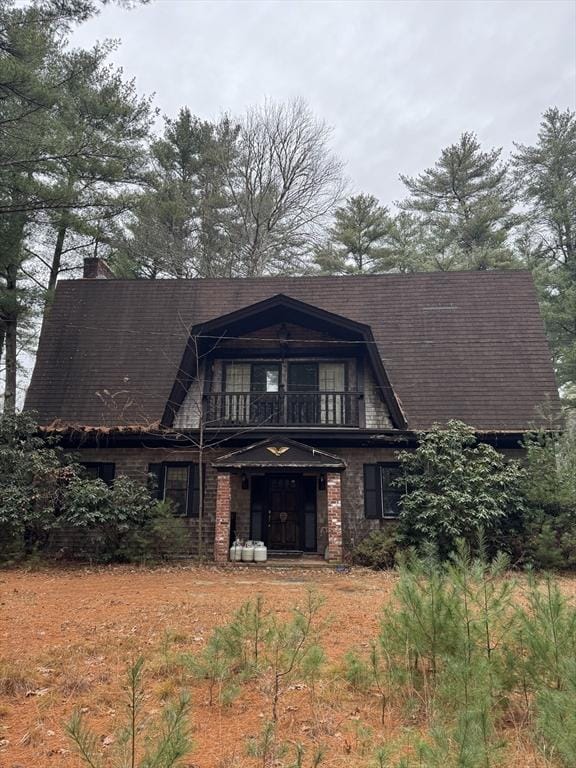 view of front of home with a balcony and a chimney