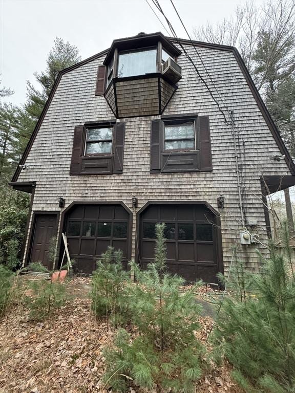 view of property exterior featuring a gambrel roof and an attached garage