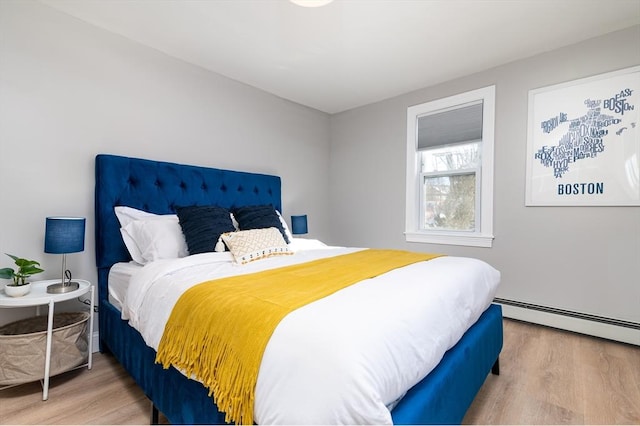 bedroom with baseboard heating and wood-type flooring