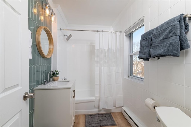 full bathroom featuring shower / bath combination with curtain, hardwood / wood-style flooring, vanity, tile walls, and a baseboard heating unit