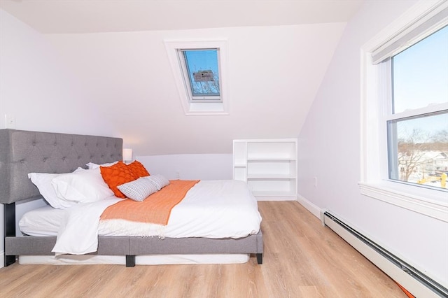 bedroom featuring lofted ceiling, a baseboard heating unit, and light hardwood / wood-style flooring