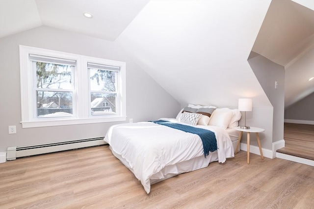 bedroom featuring lofted ceiling, a baseboard heating unit, and light wood-type flooring