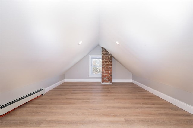 bonus room with vaulted ceiling, a baseboard heating unit, and light hardwood / wood-style floors