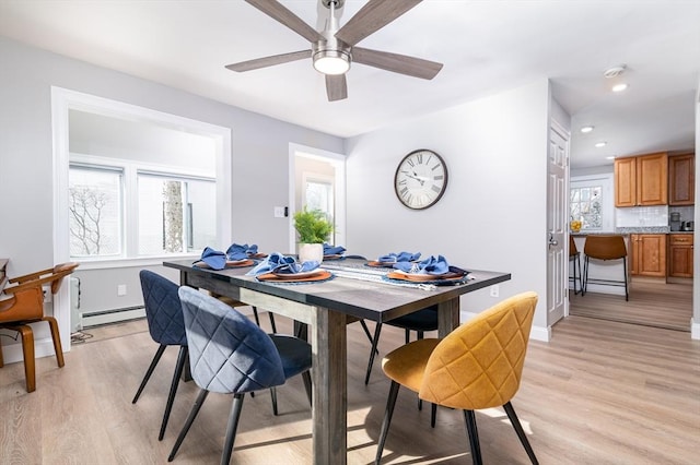 dining area featuring ceiling fan, baseboard heating, light hardwood / wood-style flooring, and plenty of natural light