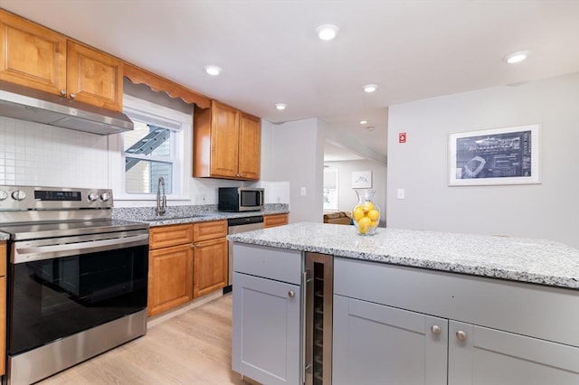 kitchen with beverage cooler, gray cabinetry, appliances with stainless steel finishes, light stone countertops, and backsplash