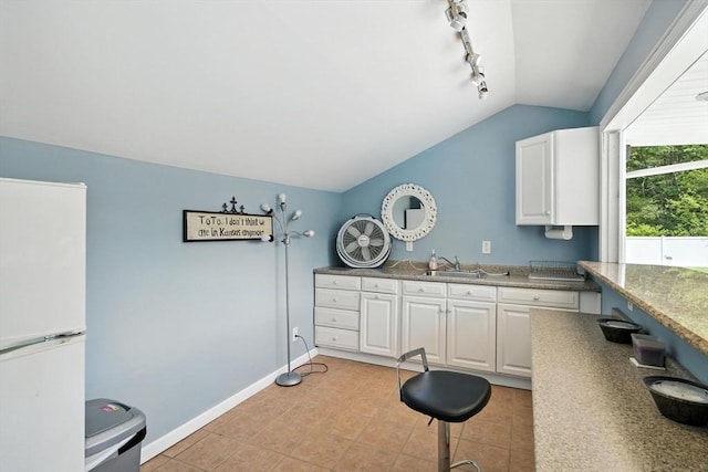 644 Stony Hill Rd, Wilbraham, MA 01095 - kitchen with freestanding refrigerator, lofted ceiling, white cabinetry, rail lighting, and light tile patterned floors