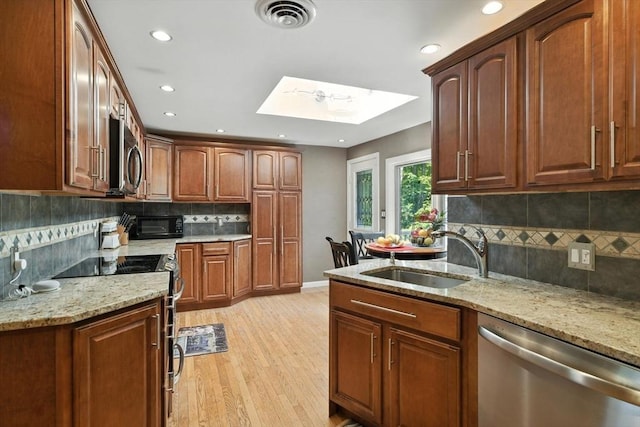 644 Stony Hill Rd, Wilbraham, MA 01095 - kitchen with stainless steel appliances, a skylight, backsplash, light stone countertops, and light wood finished floors