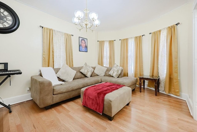 living area featuring a chandelier, baseboards, and light wood finished floors