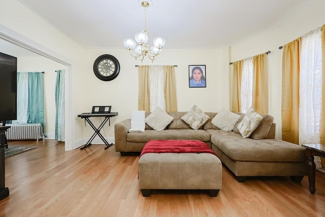 living area featuring light wood finished floors, an inviting chandelier, and radiator