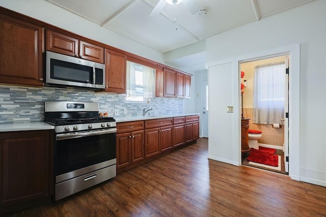 kitchen with tasteful backsplash, dark wood-type flooring, stainless steel appliances, light countertops, and a sink