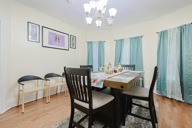 dining space with baseboards, light wood finished floors, and an inviting chandelier