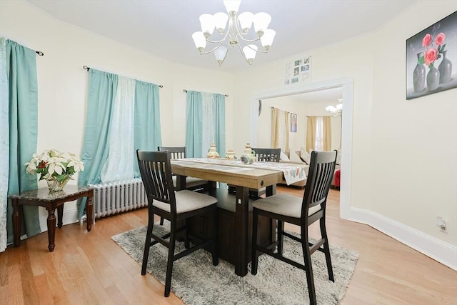 dining area featuring light wood-style floors, radiator, baseboards, and an inviting chandelier