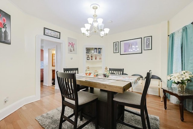 dining area featuring a chandelier, light wood-style flooring, and baseboards