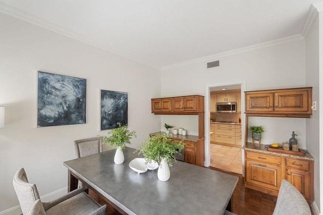dining room with crown molding, baseboards, and visible vents