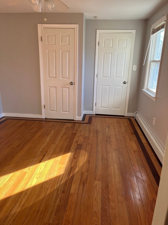 foyer entrance with baseboard heating, ceiling fan, and hardwood / wood-style floors