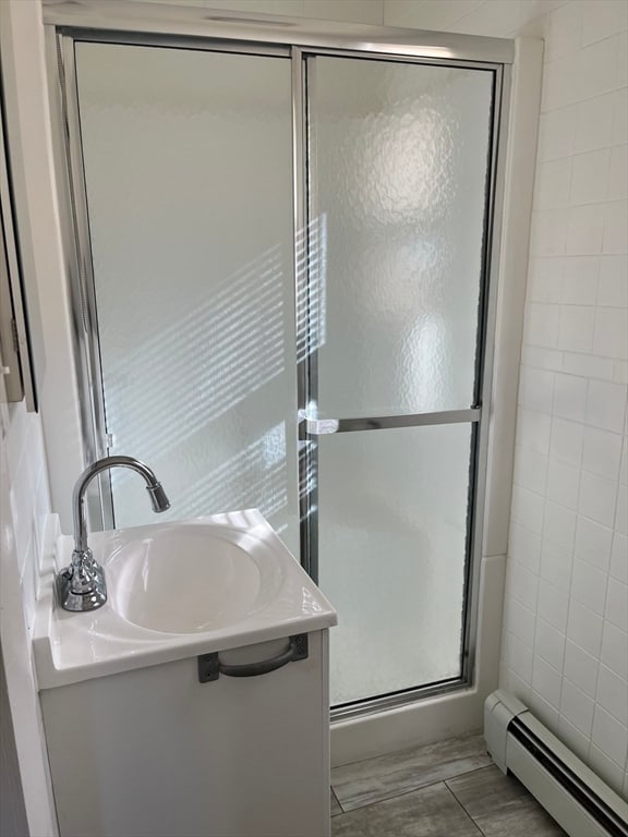 bathroom featuring vanity, an enclosed shower, tile walls, and a baseboard radiator