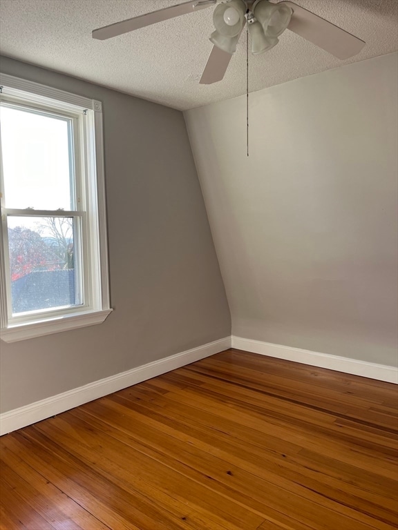 spare room with hardwood / wood-style floors, ceiling fan, and a textured ceiling